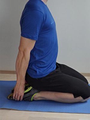 A man performing a kneeling shin stretch.