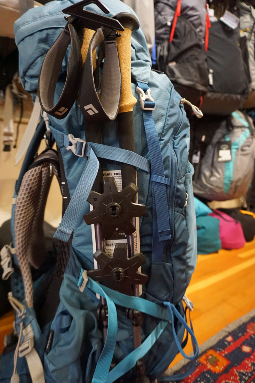 Osprey backpack upper and lower side compression straps securing hiking poles.