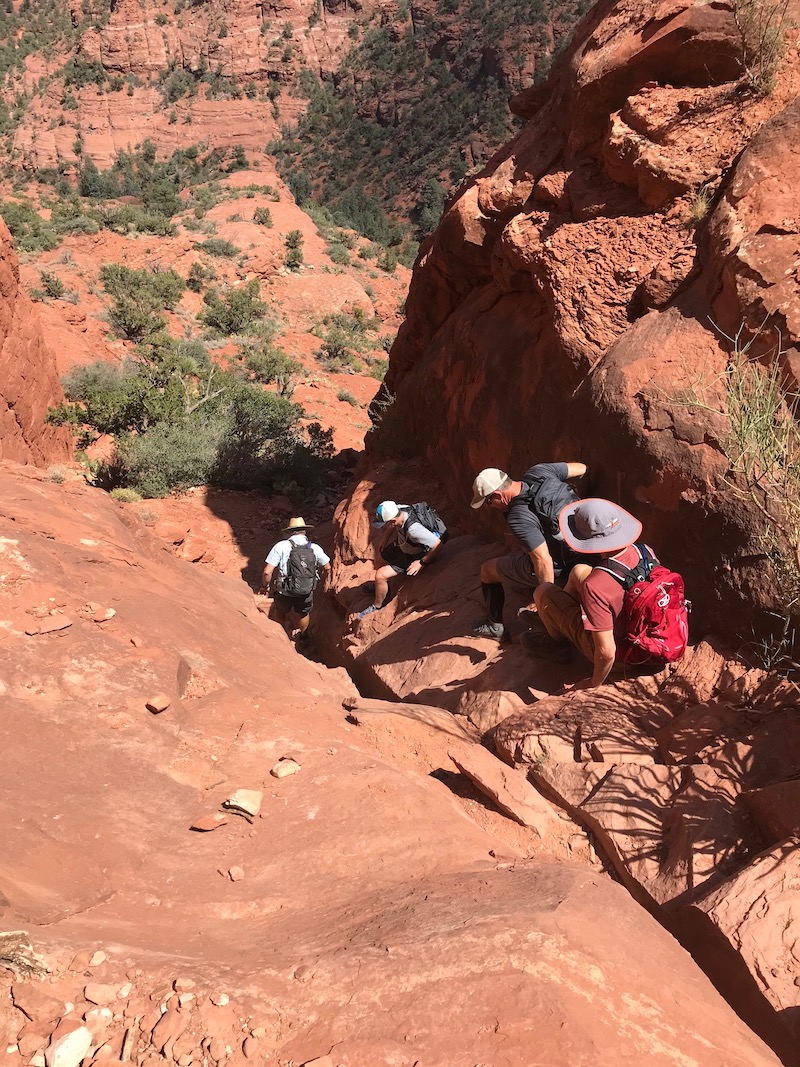 Hikers coming down a steep scramble from top of Cathedral Rock in Sedona.