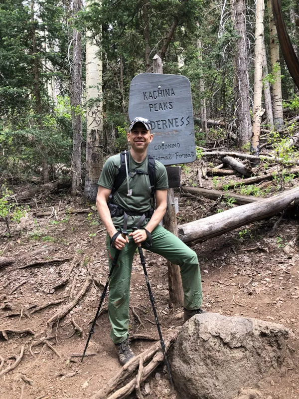 Male hiker standing in front of Kachina Peaks Wilderness sign