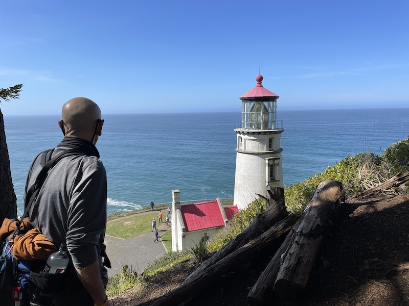Man on the Oregon Coast Trail looking at Heceta Head Light House.
