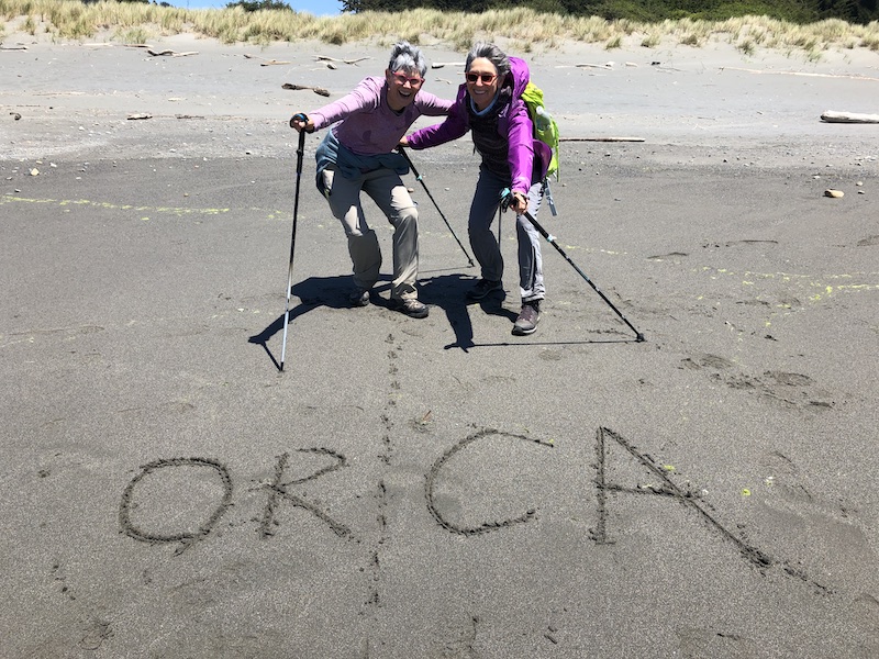 Hikers celebrating reaching Oregon/California state line on Oregon Coast.