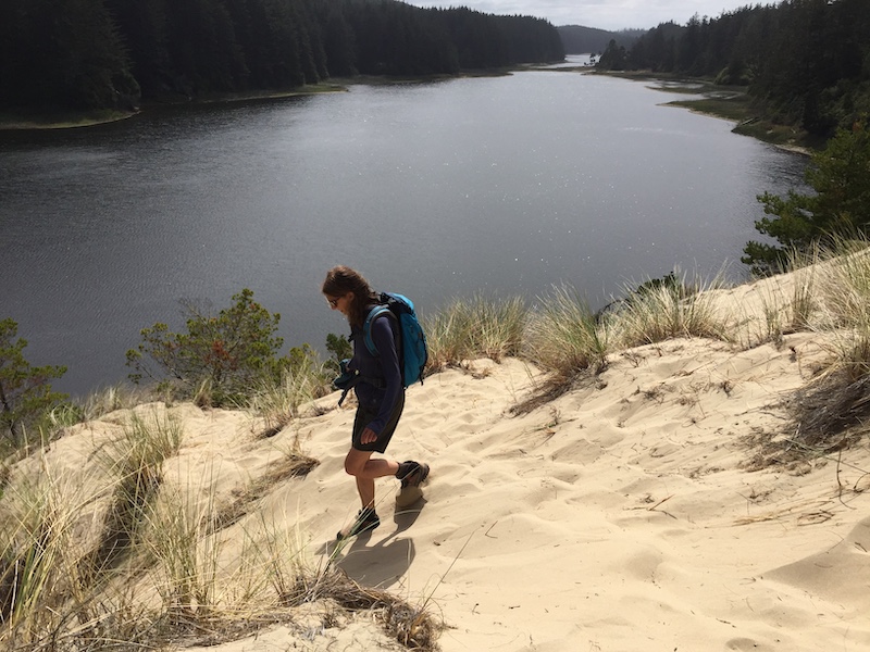 Hiker walking in sand at Threemile Lake in Oregon Dunes National Recreation Area.